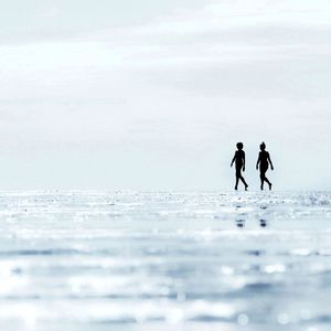 2 woman silhouettes walking on the beach during low tide