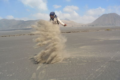 Man surfing on desert against sky