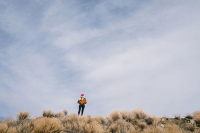 Rear view of woman standing on field against sky