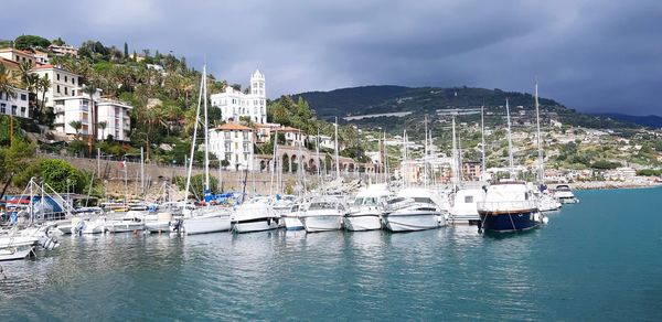 Sailboats moored in harbor against buildings in city