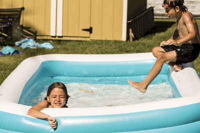 Playful siblings in wading pool at lawn