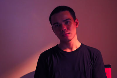 Portrait of young man standing against red background