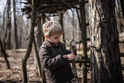 Boy standing by tree trunk