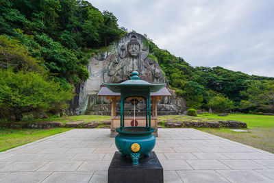 Buddha statue on footpath against sky