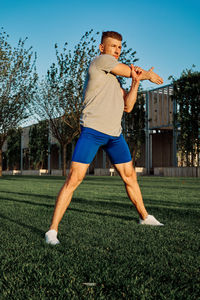 Full length of man playing soccer on grass against sky