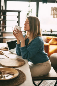 A young woman enjoys coffee in the morning and works at her laptop. work at home, online business, 