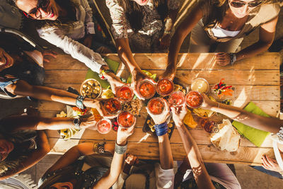 Directly above shot of friends toasting drinks at dining table