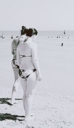 Rear view of woman standing on beach against sky