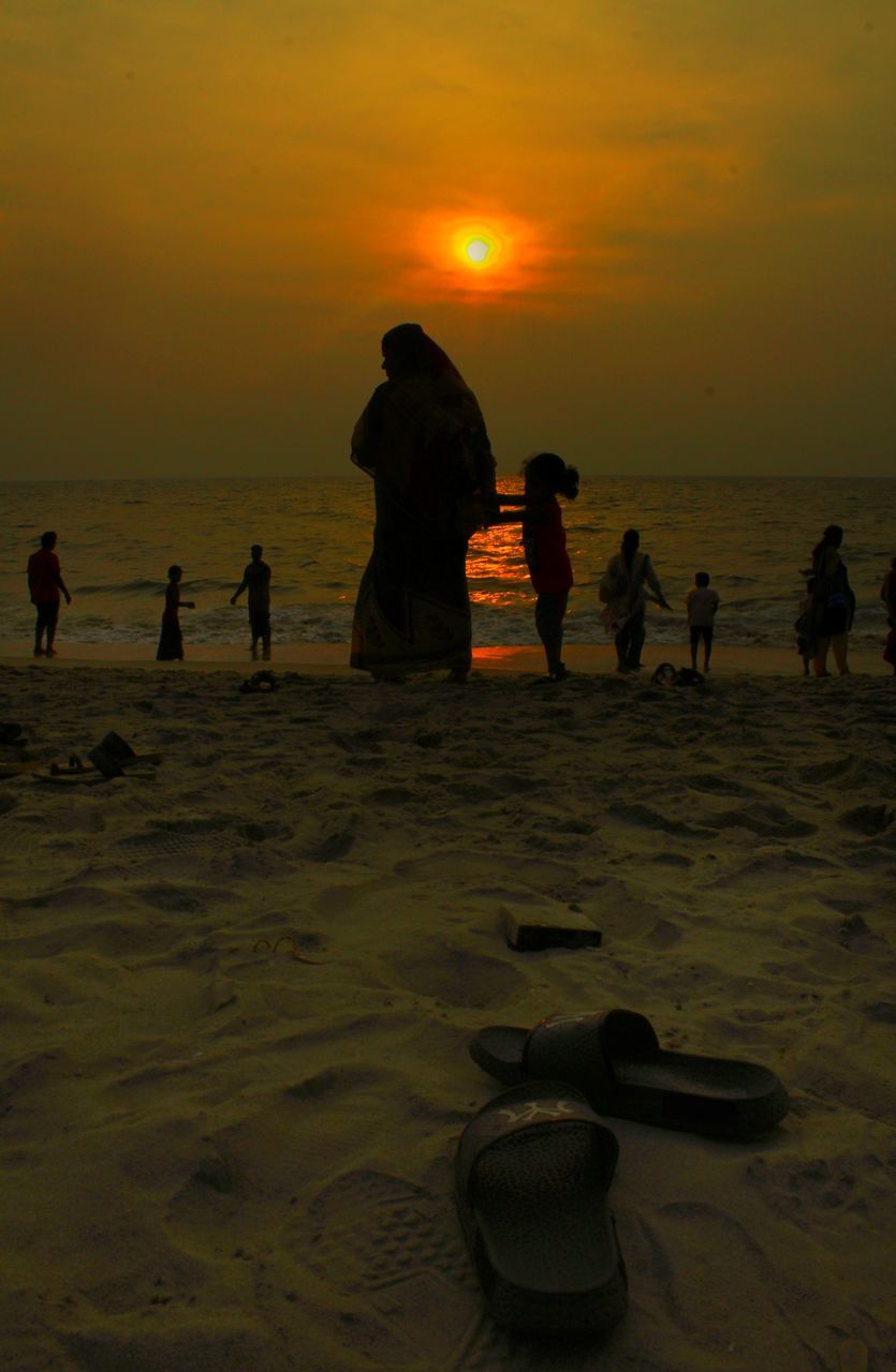 SILHOUETTE PEOPLE ON BEACH AGAINST ORANGE SKY