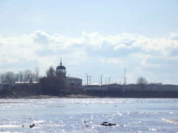 View of buildings by sea against cloudy sky