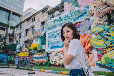 Full length of woman standing against graffiti wall