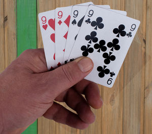 Cropped hand holding cards at wooden table