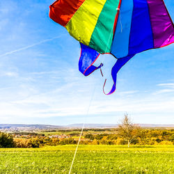 Multi colored umbrella on field against sky