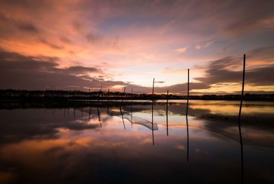 Scenic view of lake against dramatic sky during sunset