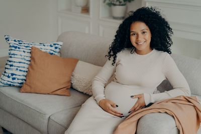 Portrait of smiling woman sitting on sofa at home