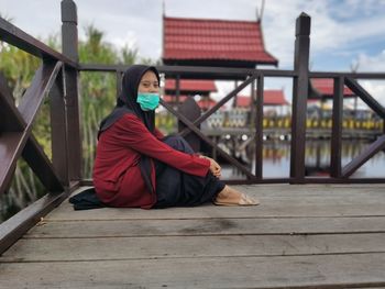 Portrait of young woman sitting on boardwalk