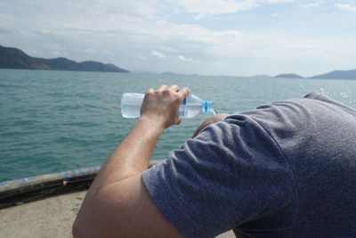 Close-up of man washing head with water while standing in boat on sea