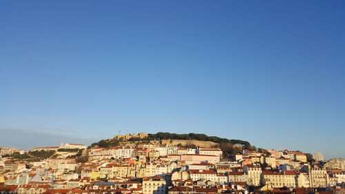 Buildings in city against clear blue sky