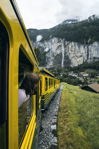 Woman peeking from train window passing by mountains
