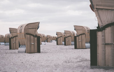 Hooded beach chairs on sand against sky