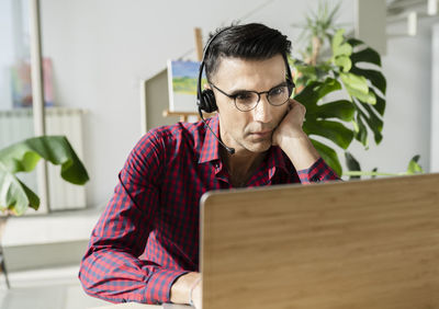 Businessman with headset using laptop at home