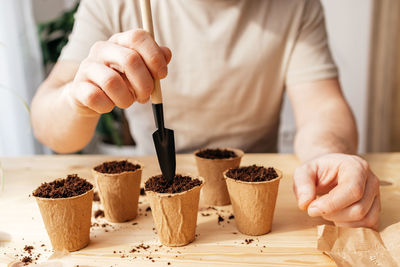 The process of planting tomato seeds in peat environmental cups. the close -up of the hands of a man