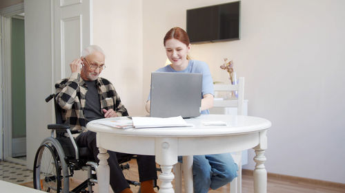 Nurse and senior man looking at laptop