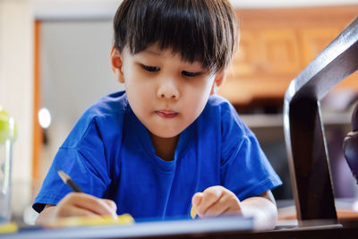 Close-up of boy writing at home