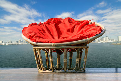 Close-up of red chair in sea against sky