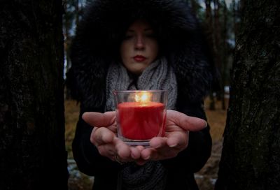 Portrait of woman holding candle outdoors