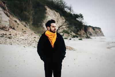 Young man looking away while standing on land against sky