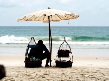 Rear view of people on beach against sky