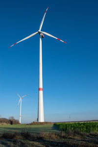 Windmill on field against clear blue sky