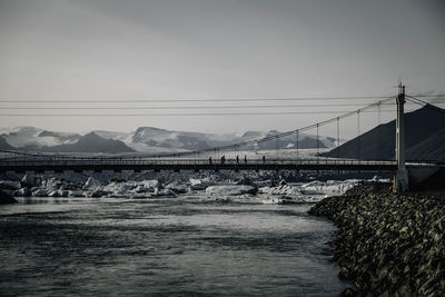 Bridge over river against sky during winter