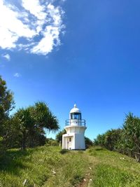 Lighthouse amidst trees and buildings against sky