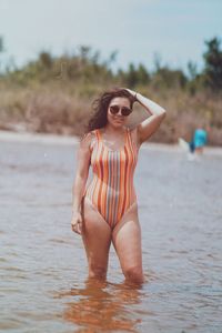 Young woman standing in sea against sky