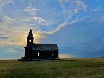 Building on field against sky