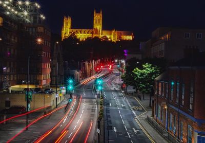 Light trails on road along illuminated buildings at night