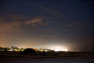 Scenic view of illuminated field against sky at night