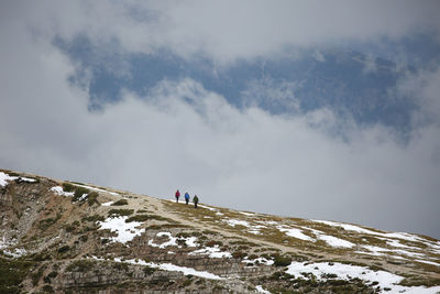 Hikers walking on snow covered mountain against sky