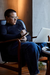 Young man using laptop while sitting on sofa at home