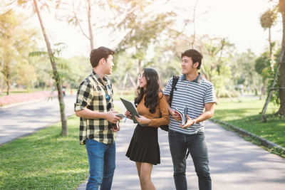 Students talking while standing on footpath at public park