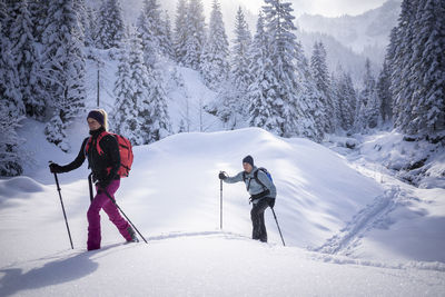 Mid adult woman ski touring with man during sunny day