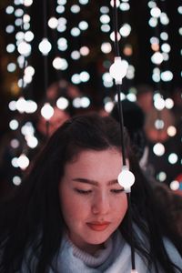 Woman amidst illuminated lighting equipment at night