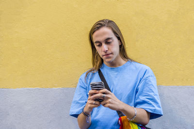 Man using mobile phone while wearing a belt bag with the lgbt rainbow flag.