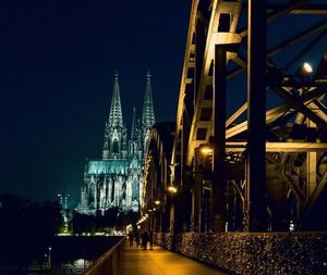 Illuminated temple by building against sky at night