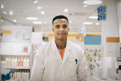 Portrait of smiling male owner wearing lab coat standing in medical store