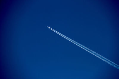 Low angle view of airplane flying against clear blue sky