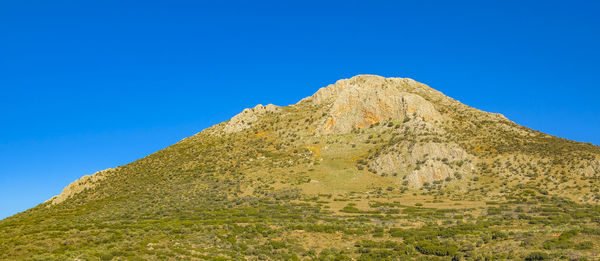 Low angle view of mountain against clear blue sky