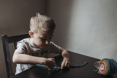 Young boy knitting with fingers at home during isolation